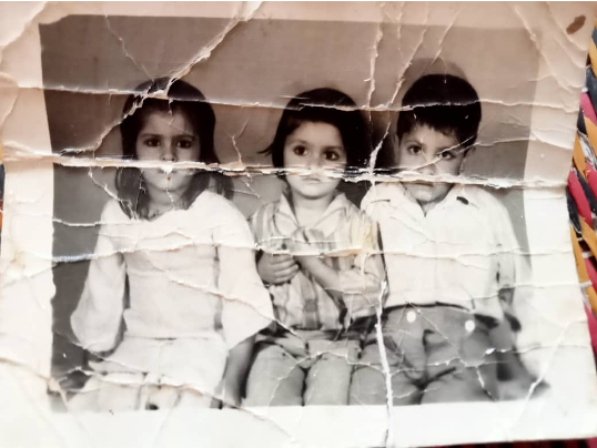 Heavily creased black and white photo of three children. This image is of Lailey and her two brothers. 